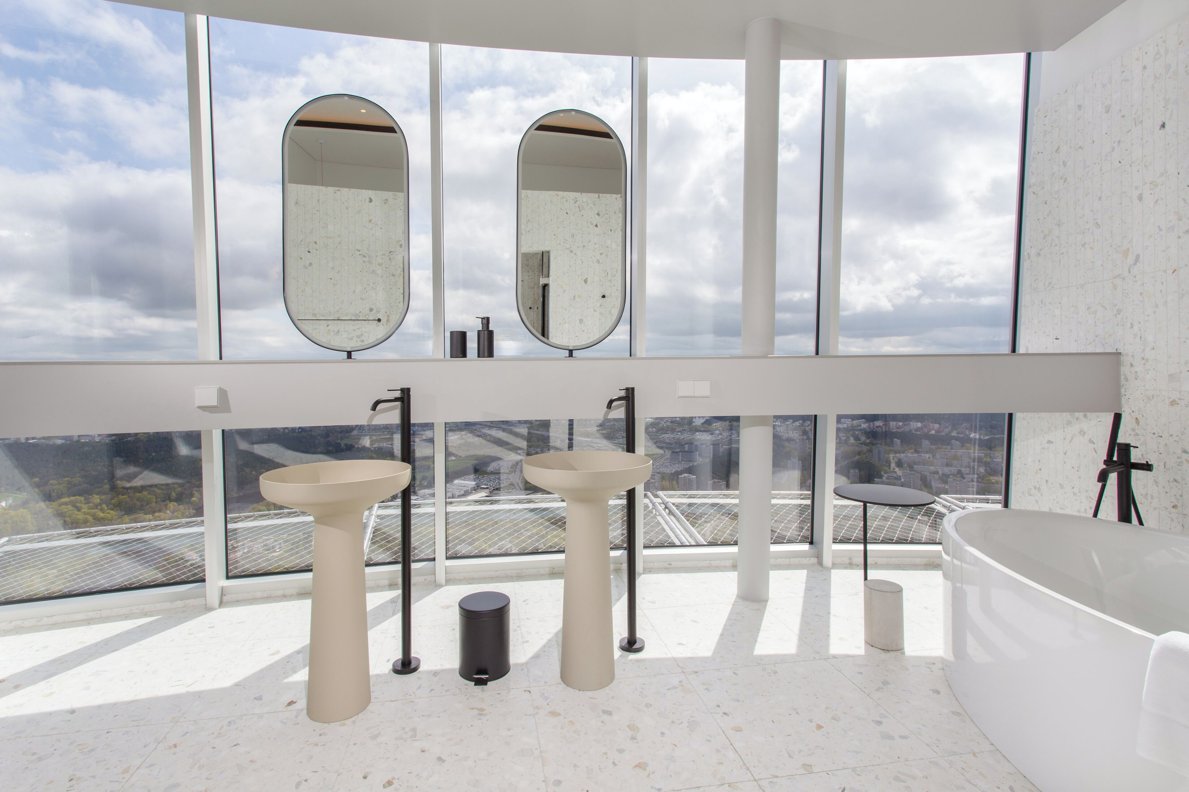 A modern bathroom with two sinks, a large mirror, and a freestanding bathtub.