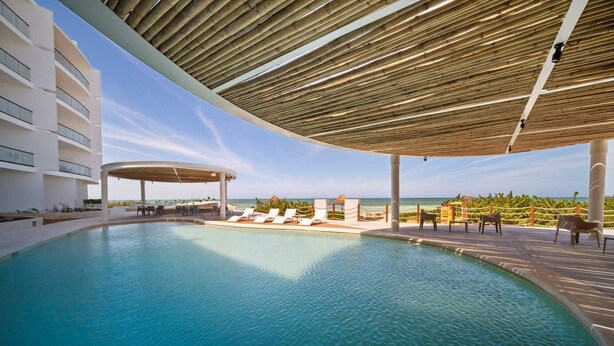 A pool area with lounge chairs and a view of the ocean. - 4-Bedroom Beachfront Apartment (San Bruno)