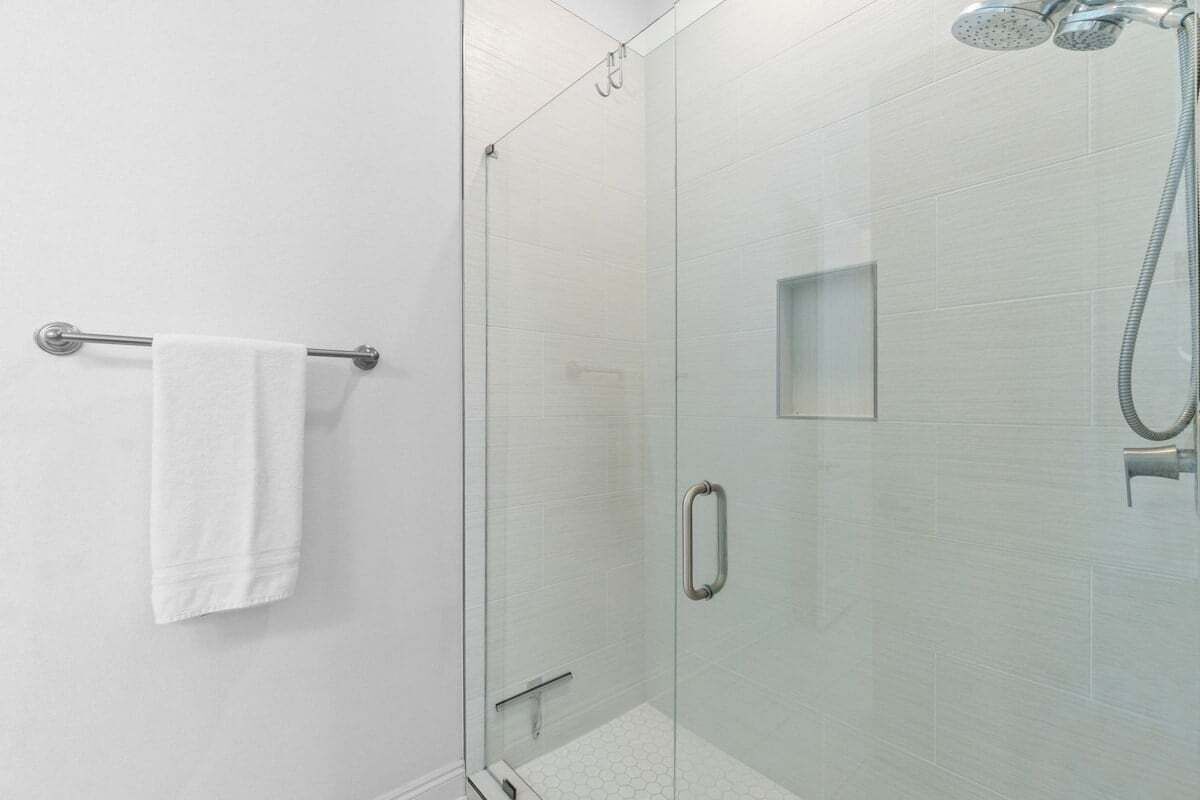 Une salle de bain moderne dotée d’une douche à parois de verre, d’un porte-serviettes et d’un pommeau de douche à main.