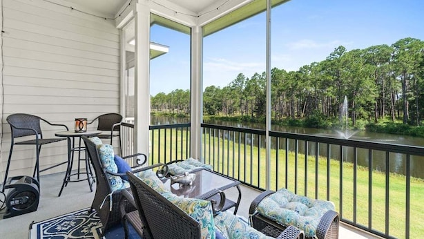 A covered outdoor area with wicker furniture and a view of a lake and forest. - Fall Deals + Snowbird Rates | Lake View, Pool, Close to the Beach (Santa Rosa Beach)
