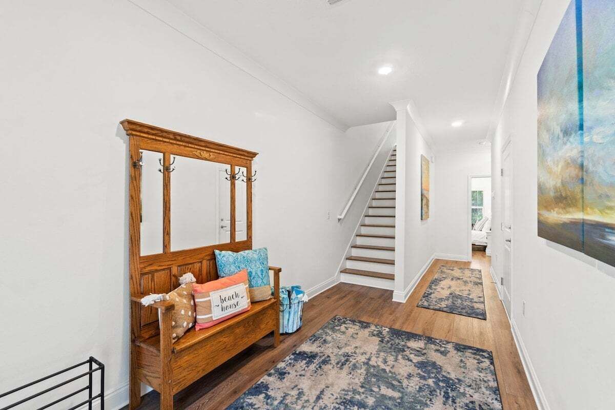 A hallway with a wooden bench, a staircase, and a painting on the wall.