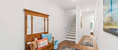 A hallway with a wooden bench, a staircase, and a painting on the wall.