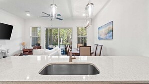 A modern kitchen with a large island, stainless steel sink, and pendant lighting. - Fall Deals + Snowbird Rates | Lake View, Pool, Close to the Beach (Santa Rosa Beach)