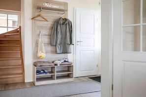 Un couloir avec un banc en bois, un porte-manteau et une pancarte de bienvenue.