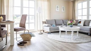 Un salon moderne avec un canapé, une table basse ronde, une lampe et une vue dégagée grâce à de grandes fenêtres.