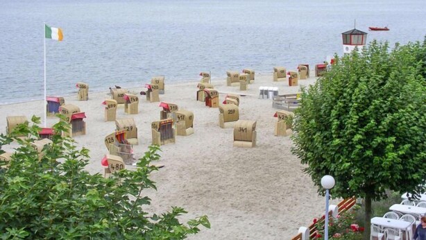 Una playa con cajas de cartón numeradas, una torre de salvavidas y una bandera.