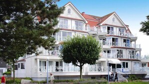 Un hotel de varios pisos con balcones, un patio central y un jardín bien cuidado.