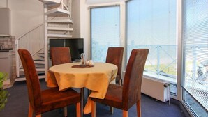 Un comedor con una mesa redonda, cuatro sillas y una escalera de caracol al fondo.