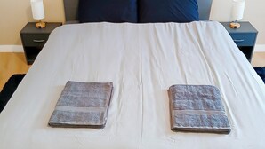A neatly made bed with a white duvet and two folded towels on the bed. - Appartement T2 55m2 Plein Centre St-brieuc (Saint-Brieuc)
