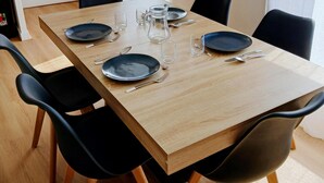 A dining area with a wooden table set for four, surrounded by black chairs, with a window in the background. - Appartement T2 55m2 Plein Centre St-brieuc (Saint-Brieuc)