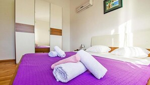 Una habitación de hotel con cama, armario, mesita de noche y un cuadro en la pared.
