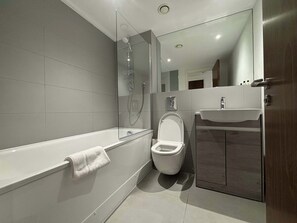 A modern bathroom with a bathtub, toilet, and sink.