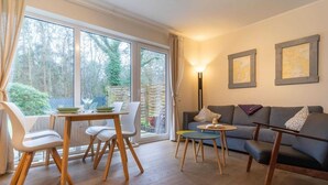 Een moderne woonkamer met een bank, stoelen, een klein tafeltje en een lamp.
