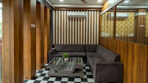 Un salon moderne avec un canapé gris, une table basse en verre agrémentée d’une plante et un ventilateur de plafond.