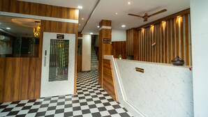 Un espace d’accueil avec un sol à carreaux, un lambris en bois, un comptoir d’accueil et un escalier menant à la salle à manger.