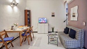 Un espacio habitable compacto con comedor, sofá y televisión.