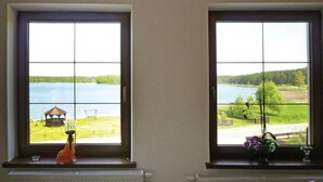 Two windows with a view of a lake, a gazebo, and a grassy area. - Comfortable holiday apartment with a lake view (Lipnica)