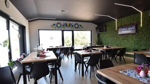 A restaurant with wooden tables and black chairs, a green wall with a floral design, and a sign reading "Dobri mȃl Kiełdrowice". - Comfortable holiday apartment with a lake view (Lipnica)