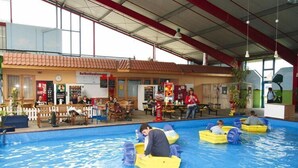 En indendørs swimmingpool med gule både og mennesker i dem.