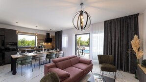 Una sala de estar moderna con sofá, sillas, comedor y cocina.