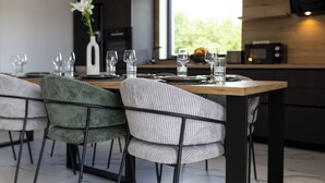 Comedor moderno con una mesa de madera preparada para cuatro personas, rodeada de sillas tapizadas.