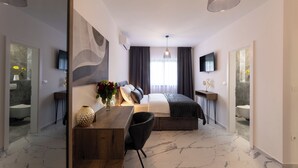 Un dormitorio moderno con cama, mesitas de noche, un escritorio, una silla y un televisor.