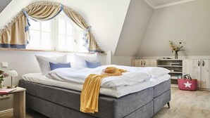 A bedroom with a bed, a nightstand, a dresser, and a window with curtains. - Premium-Ferienhaus in Fuhlendorf (Fuhlendorf)