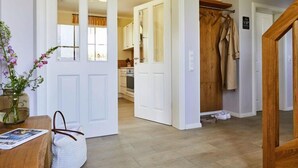 A hallway with a wooden door, a white door, and a coat rack. - Premium-Ferienhaus in Fuhlendorf (Fuhlendorf)