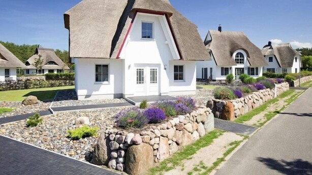 A row of white houses with thatched roofs and stone walls.