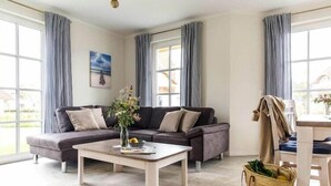 A modern living room with a sectional sofa, a coffee table, and a dining area.