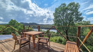 A wooden deck with a table and chairs overlooking a lake and forest.