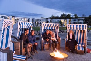 Guests can gather around the fire pit in a social area with comfortable beach chairs.