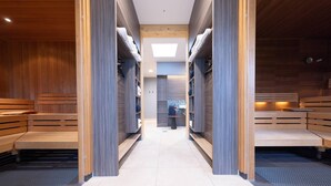 Zona de sauna con bancos y estantes, un tragaluz central y una persona al fondo.