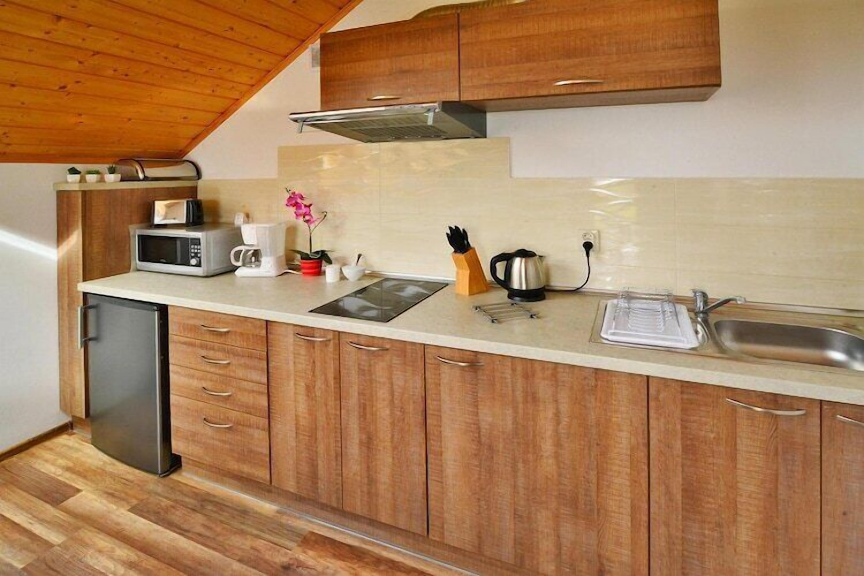 A compact kitchen with wooden cabinets, a built-in microwave, a coffee maker, and a kettle.