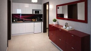 Une cuisine moderne avec des meubles blancs, un meuble rouge, un four à micro-ondes et une machine à café.