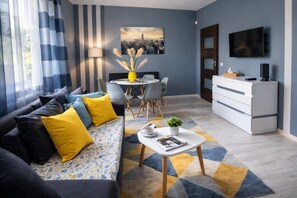 A modern living room with a sofa, coffee table, and dining area. - Apartment in Rewal near Blue Flag Beach (Rewal)
