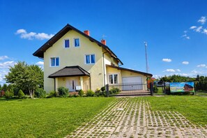 A two-story house with a paved driveway, a fenced yard, and a clear sky. - Apartment in Rewal near Blue Flag Beach (Rewal)