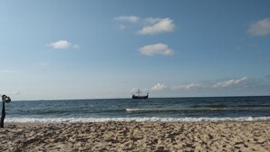 A beach with a boat in the distance and a clear sky. - Apartment in Rewal near Blue Flag Beach (Rewal)