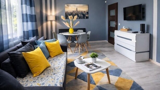 Un salon moderne comprenant un canapé, une table basse et un coin repas avec des chaises.