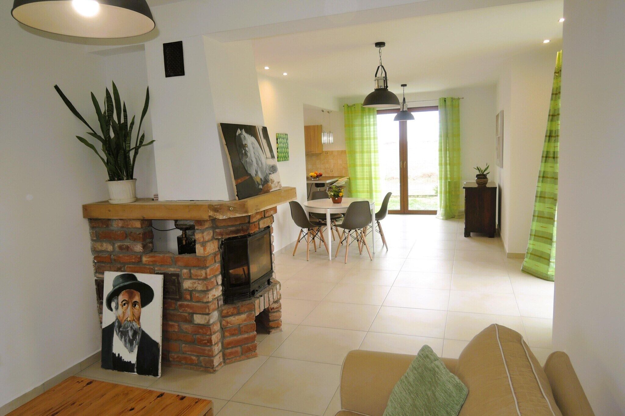 Ein Wohnzimmer mit Kamin aus Ziegelsteinen, ein Essbereich mit Tisch und Stühlen und eine Küche im Hintergrund.