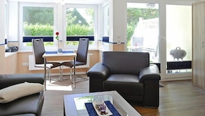 Un salon moderne comprenant un canapé, une table basse et un coin repas avec des chaises et une table.