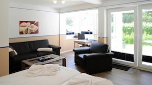Une chambre d’hôtel avec un lit, un canapé noir, un fauteuil plus petit, une table basse et un tableau au mur.