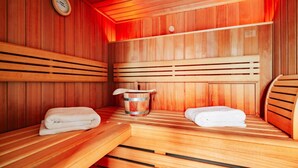 A sauna room with wooden benches, a wooden bucket, and a clock on the wall. - Ferienhäuser, Torfhaus (Torfhaus)