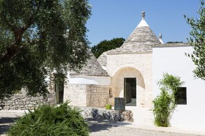 A traditional stone building with a conical roof, an arched entrance, and a small window. - Country House in Ostuni near Rosa Marina Beach (Ostuni)