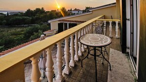 Un balcon doté d’un sol carrelé, d’une table ronde recouverte d’une nappe à motifs et d’une balustrade.
