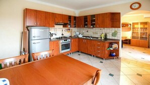 Une cuisine avec des meubles de rangement en bois, un réfrigérateur, une cuisinière et une table à manger avec des chaises.