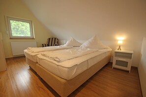 A bedroom with a bed, a nightstand, a window, and a radiator. - Ferienhof Neuendorf (Lütow)