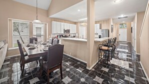 A spacious kitchen with white cabinets, a central island, and a dining area with a table set for four.