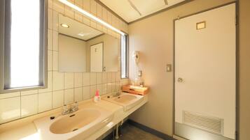 A bathroom with two sinks, a mirror, a hairdryer, and a door.