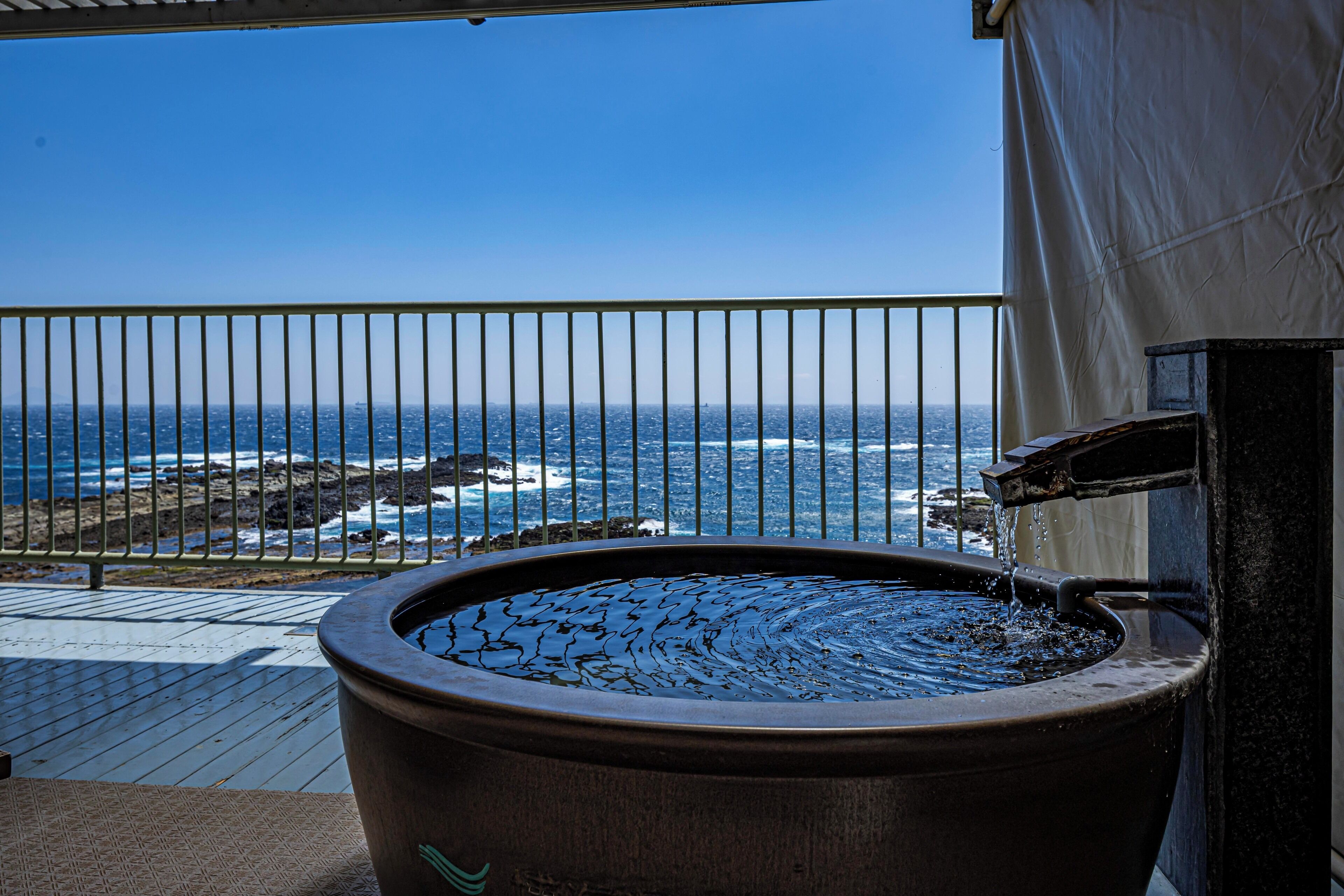 Ein Whirlpool auf einem Balkon mit Blick auf das Meer.